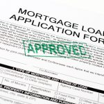 A paper with mortgage oan application form on the top in bold letters with a paragraph written underneath. There is a green stamp stating approved in capitalized letters (diagonally)
