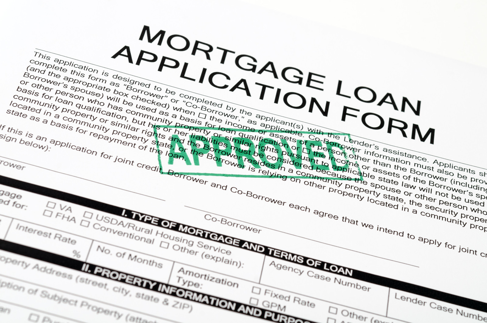 A paper with mortgage oan application form on the top in bold letters with a paragraph written underneath. There is a green stamp stating approved in capitalized letters (diagonally)
